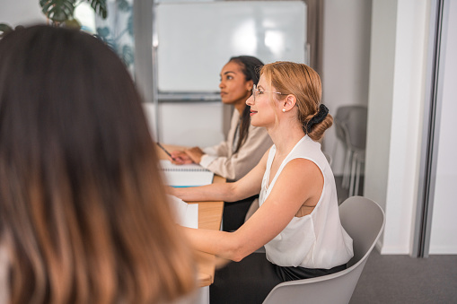 A group of multiracial professionals, distinguished by their good looks, deep in discussions about business strategies within a corporate office. Utilizing laptops and wireless technology in a meeting, they present a formal business demeanor.