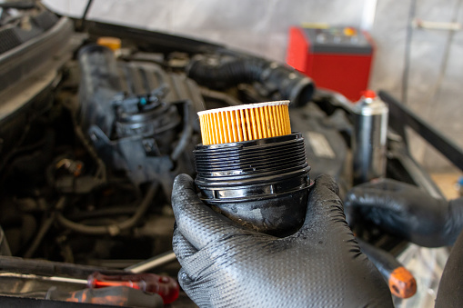 Car oil filter change. Mechanic man holding car engine oil filter in his hand