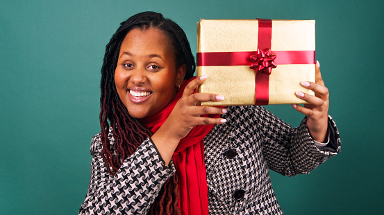 Excited young woman holds gift box and reveals face, Christmas present studio. High quality photo