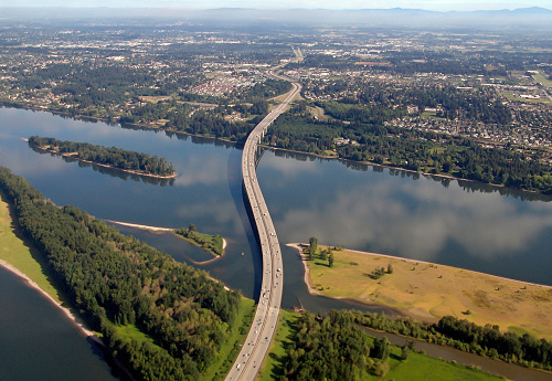 An arial view looking North of Interstate 205 Glenn Jackson Bridge and War Vetrans Memorial Freeway spanning the Columbia River and linking Oregon and  Washington in the Pacific Northwest. Washington at top with Oregon at bottom of photo.