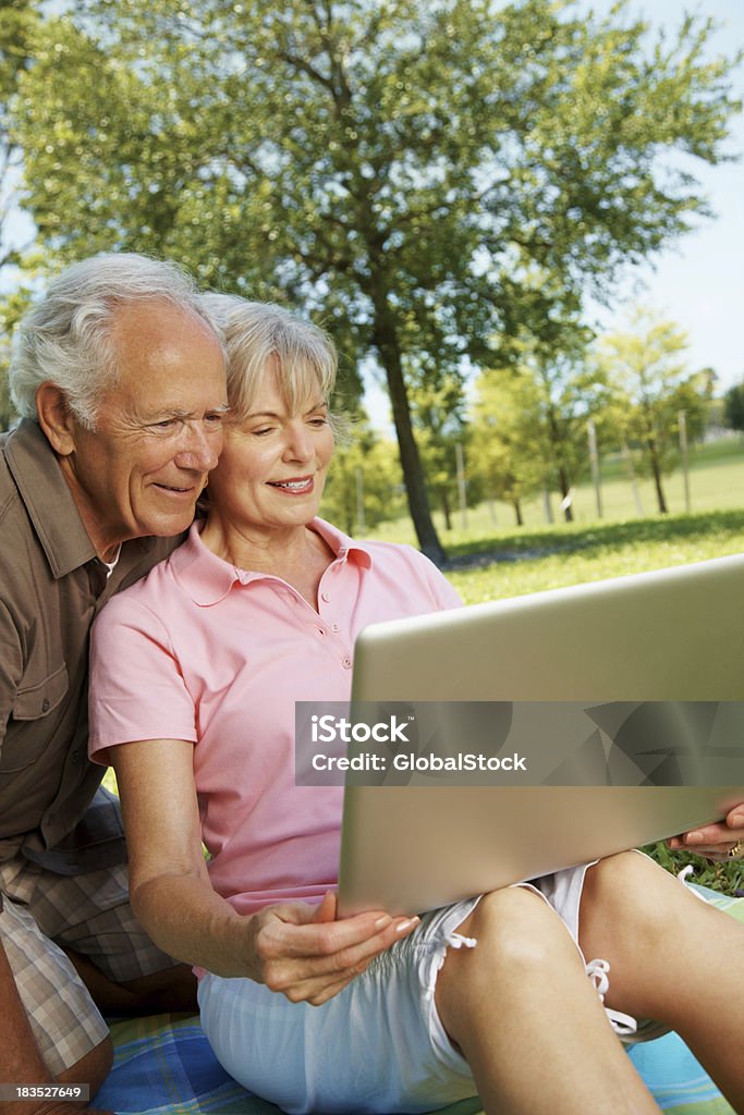 Casal sentado no parque e usando computador portátil - Royalty-free 70 anos Foto de stock