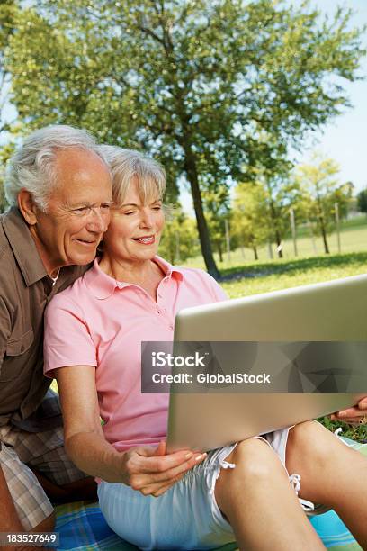 Casal Sentado No Parque E Usando Computador Portátil - Fotografias de stock e mais imagens de 70 anos