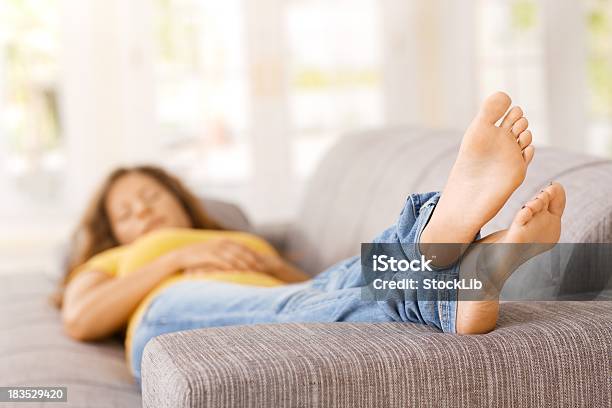 Jovem Mulher Deitada No Sofá Na Sala De Estar Dormir - Fotografias de stock e mais imagens de Pés no Ar