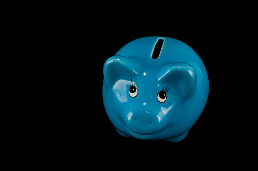 Blue piggy bank or money box isolated on a black studio background