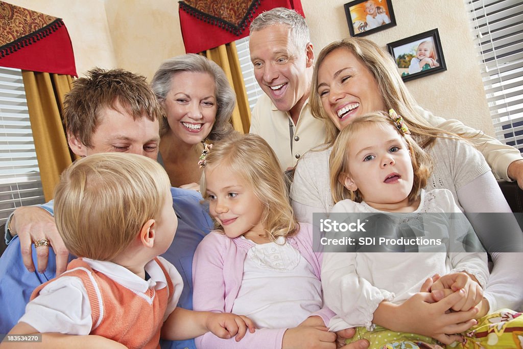 Семья с бабушкой и дедушкой, наслаждаясь время вместе в гостиной - Стоковые фото Мать роялти-фри