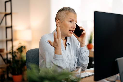 Angry woman talking on phone in home office