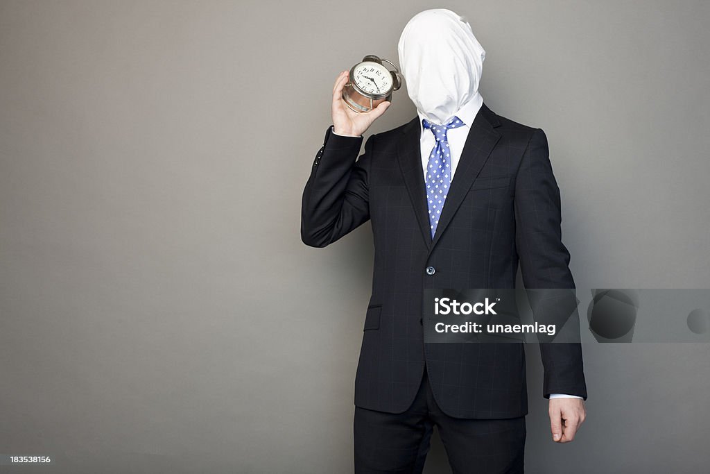 faceless man playing with a table clock portrait of a faceless man dressed in a black suit playing with a table clock Adult Stock Photo