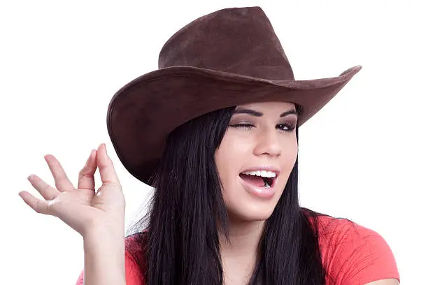 Attractive young woman wearing a cowboy hat and giving the okay hand sign and winking.