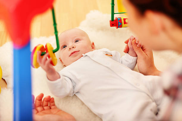 Baby using fine motor skills to play Baby playing and learning motor skills. looking around stock pictures, royalty-free photos & images