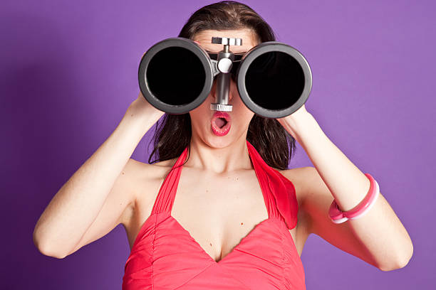 Surprised woman looking through large binocular.