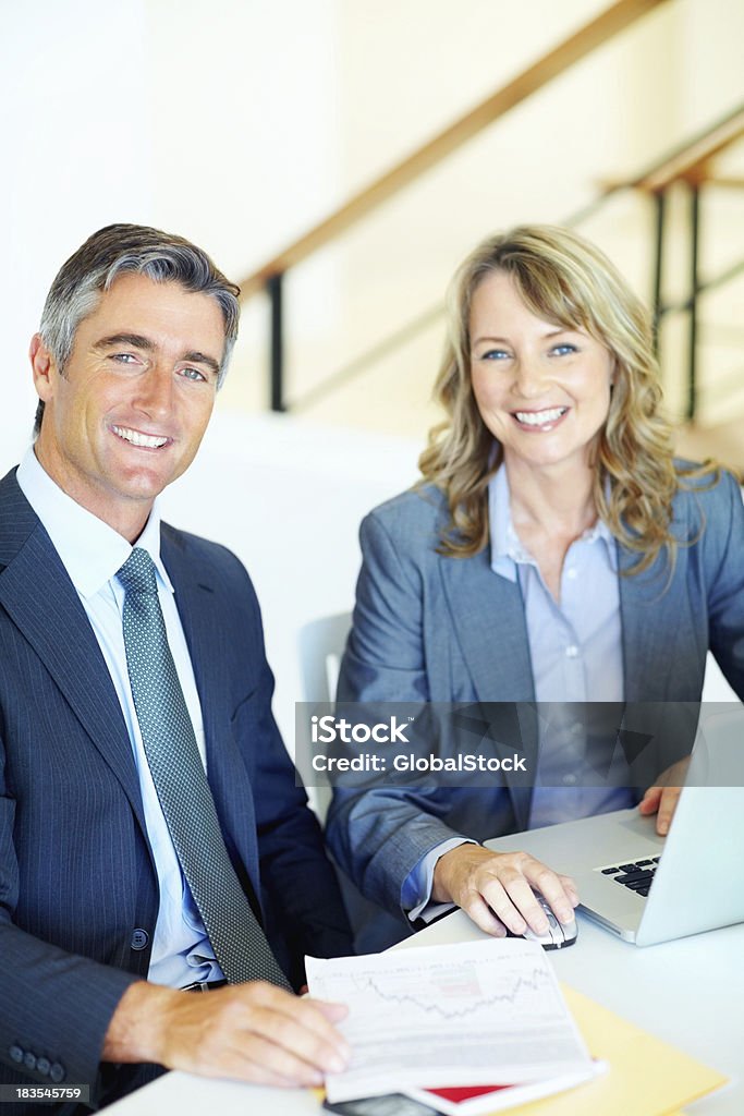 Business man and woman at desk Smiling business colleagues working on laptop 40-49 Years Stock Photo