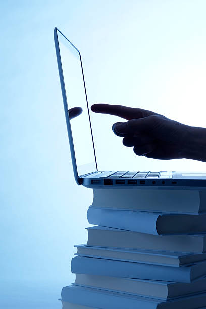 istock Blue tinted image of laptop and pointing finger on book 183546285