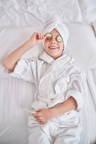 istock Boy in bathrobe demonstrating cucumber slice 1835477395