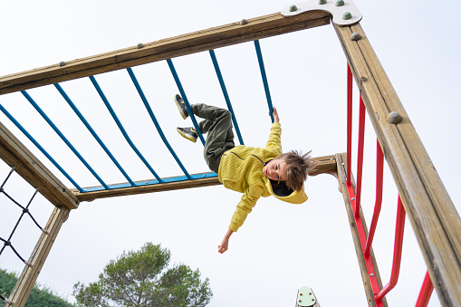 child hanging from a playground structure
