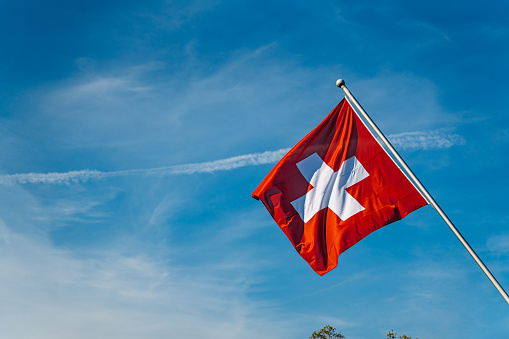 Swiss flag against the sky in Geneva, Switzerland.