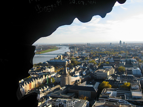 The German city of Cologne and the River Rein as seen from its cathedral with part of the delicate stonework in Silhouette.