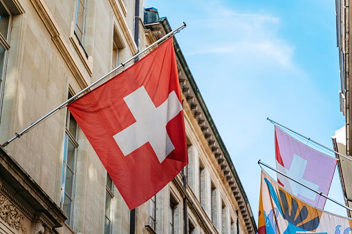 Swiss flag waving on a historic building in Geneva.