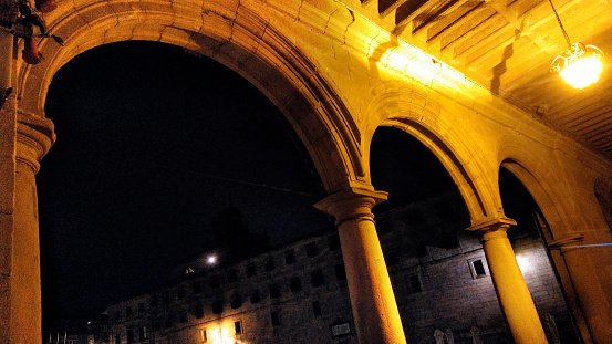 Quintana town square at night, row of stone arches .  Arcade, low angle view. Santiago de Compostela, Galicia, Spain.