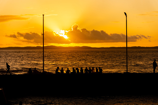 Silhouette of tourists at dramatic orange sunset against the beach. Preserved nature