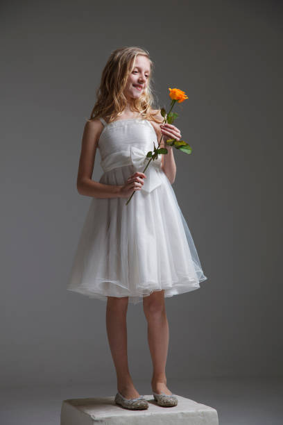 Girl giving rose for mother's day, birthday or valentine's day. Isolated on dark background.