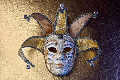 Top view of fancy golden Venetian carnival mask on golden textured surface.