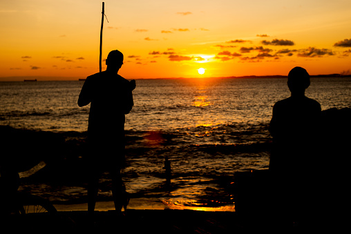 Silhouette of an unidentified person playing the Berimbau against the sunset. Romantic and beautiful end of the afternoon.