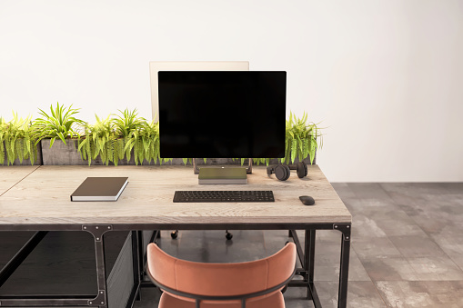 Blank monitor with keyboard and office supplies on desk in eco-friendly office. Large blank wall in the background. Copy space. Render