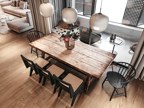 High angle view of boho loft dining room with a large rustic wooden table and chairs around, pendant lamps and vase. Terrace in the background. Render