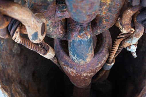 Rusty anchor chain on a ship in an anchor hawsepipe close-up.