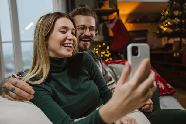 istock Young couple using smart phone during Christmastime at home 1835602997