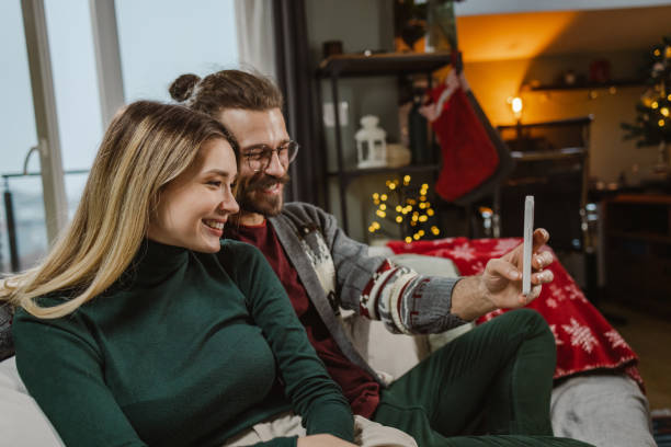 istock Young couple using smart phone during Christmastime at home 1835604581