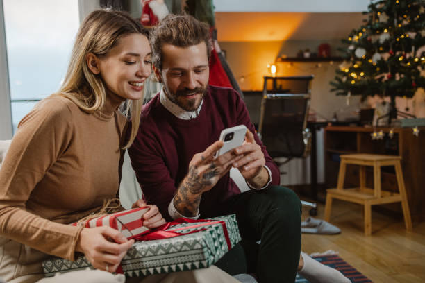 istock Lovely young couple using smart phone during Christmas time at home 1835612048