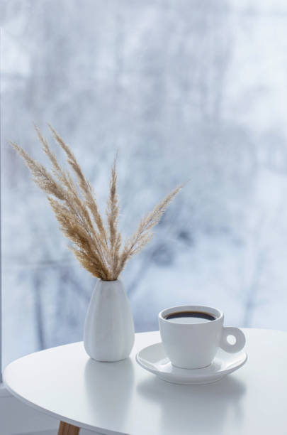istock cup of coffee on white table by window on winter 1835629735