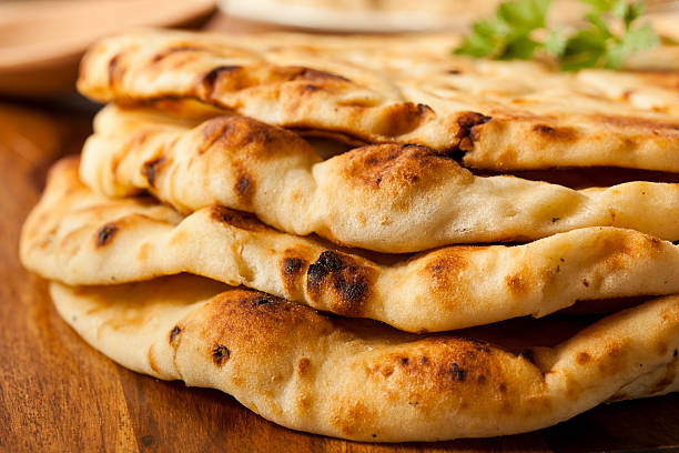 Close-up photograph of a pile of plain naan flatbreads Homemade Indian Naan Flatbread made with Whole Wheat flatbread photos stock pictures, royalty-free photos & images