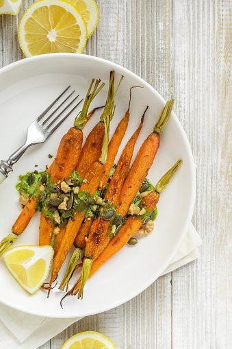 Roasted whole carrots with herb and nut pesto on a plate top view; Easter appetizer;