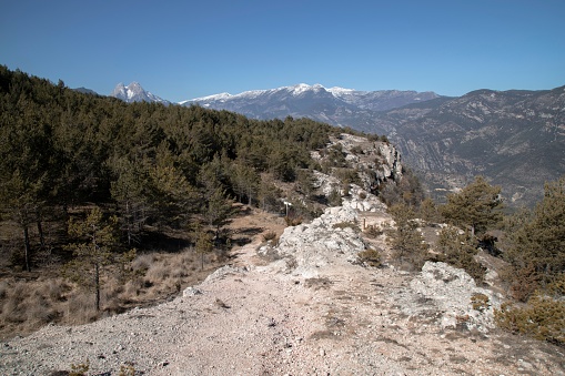 An outdoor trail meanders through a rugged landscape with vast mountain peaks in the background
