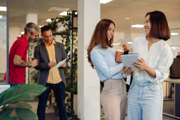 istock Diverse business women in office drinking coffee takeaway and using tablet 1835663751