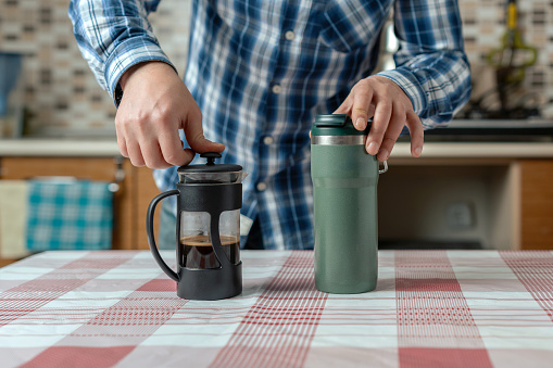 Man filling his thermos with coffee before going to work