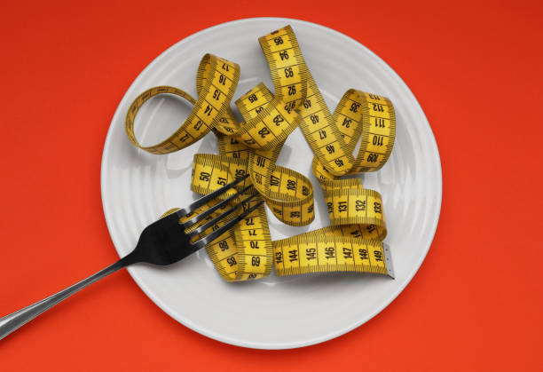 istock Plate, measuring tape and fork on red background, top view. Diet concept 1835688217