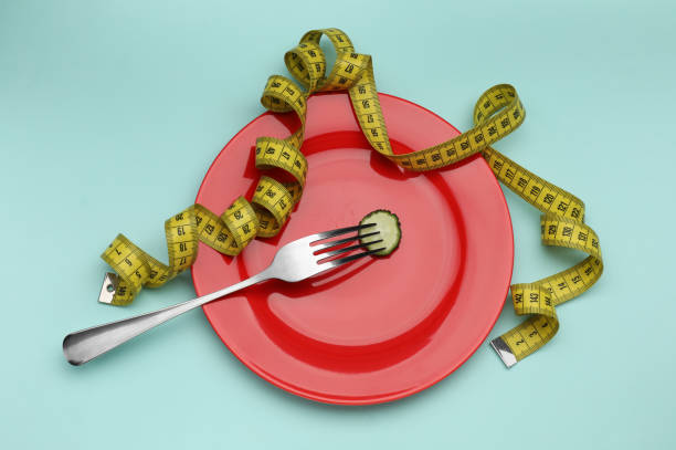 istock Plate with cucumber slice, measuring tape and fork on turquoise background, top view. Diet concept 1835688654