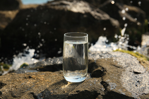 Glass of fresh water on stone outdoors