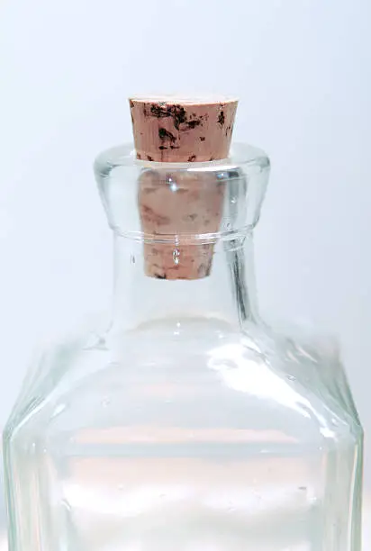 a cork stuck in the neck of a square glass bottle