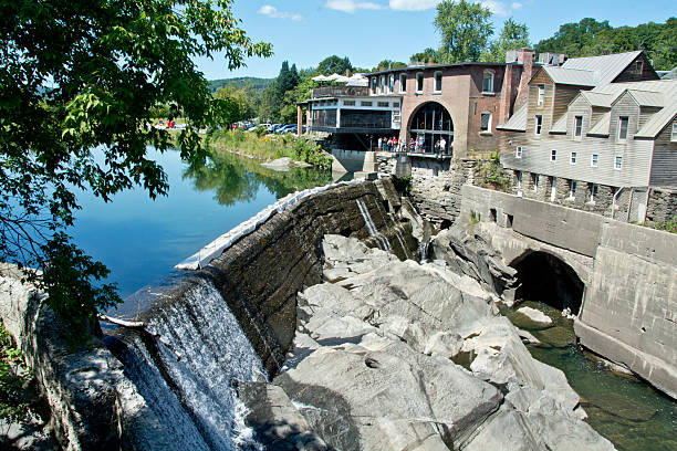 Quechee, VT, USA: On a sunny summer afternoon, tourists step outside the Simon Pearch glass factory to get a better look at the dam that supplies hydropower for the factory.