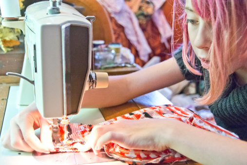 A pre-teen girl concentrates on her sewing project.