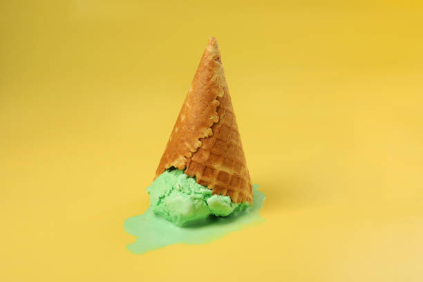istock Melted ice cream in wafer cone on pale yellow background 1835715683