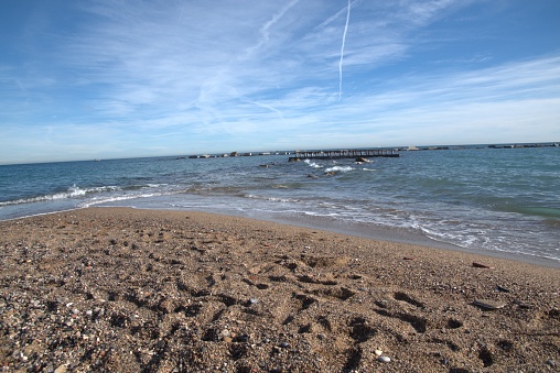Barceloneta sandy beach in November day,  breakwaters visible in the distance,  horizon over the water of the Mediterranean Sea,  blue skies