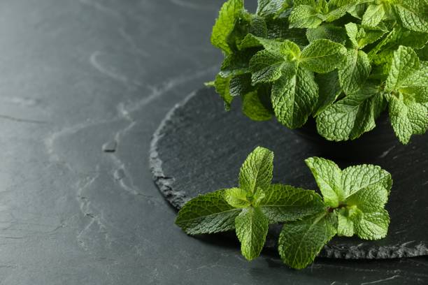 istock Fresh green mint leaves on black table, closeup. Space for text 1835722198