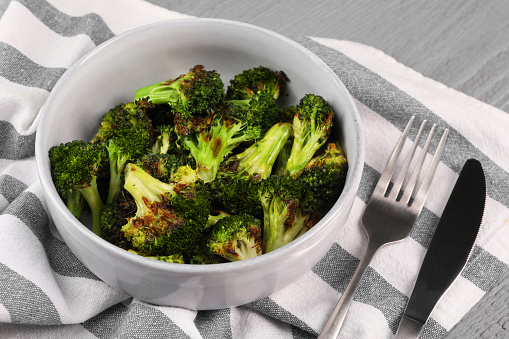 Tasty fried broccoli served on grey wooden table, closeup