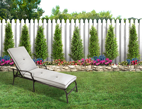 Two wooden adirondack chairs on lush green lawn with trees