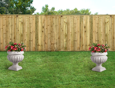 Decorative floral stands in a backyard with green grass and wood fence